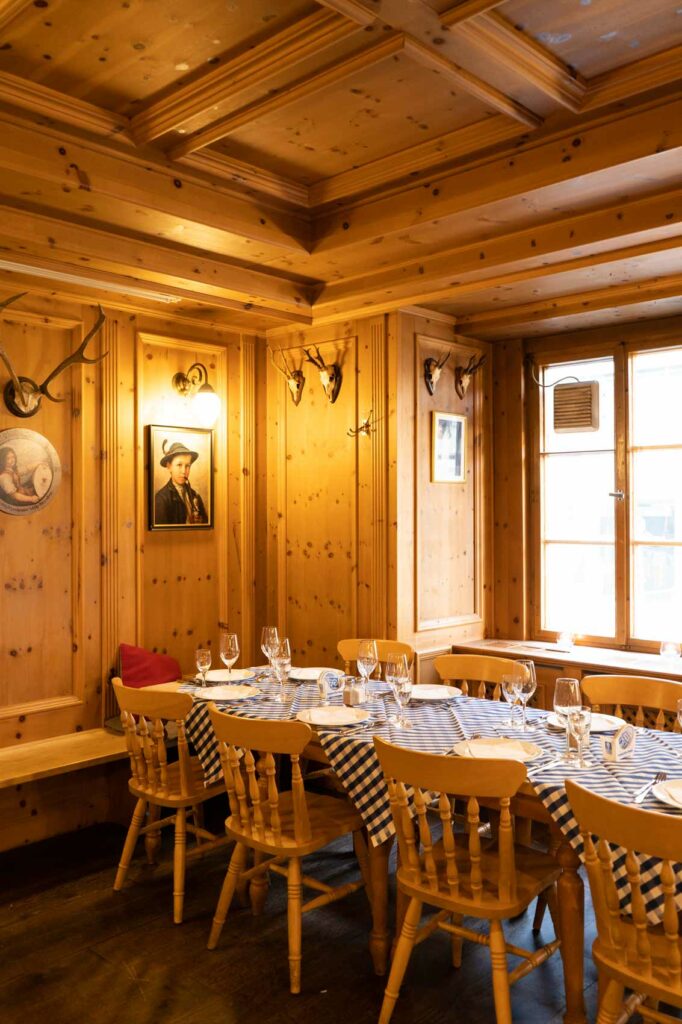 Ein helles Separee mit massiver Holzvertäfelung, Kassettendecke und festlich gedeckter Tafel schafft eine warme, traditionelle Atmosphäre.