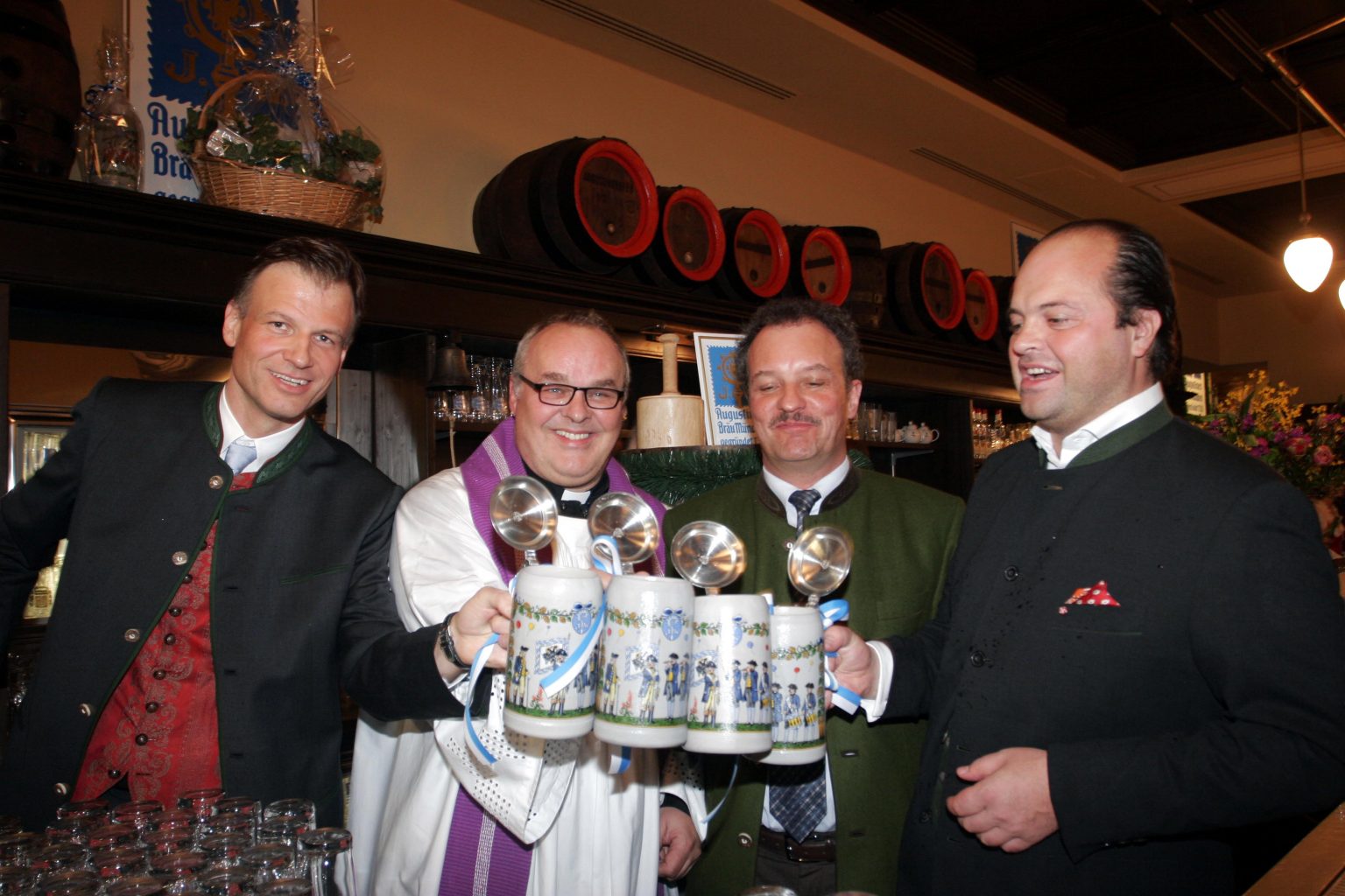 Mehrere Männer präsentieren gemeinsam frisch gezapfte Augustiner-Biere mit heller Schaumkrone.