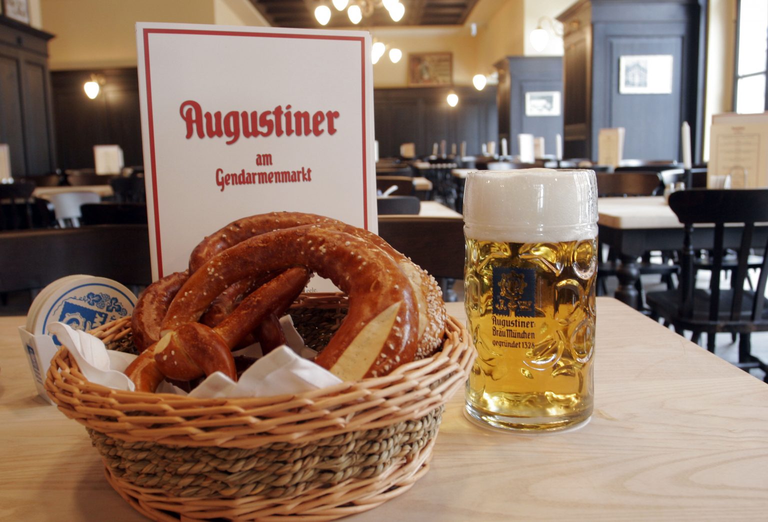 Ein frisch gezapftes Augustiner-Bier steht neben einem Korb mit knusprigen Brezeln.